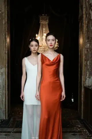 Nine Lives, One Heiress: a looping clip of an elegant dual portrait — two women in white and crimson gowns beneath a gilded chandelier.